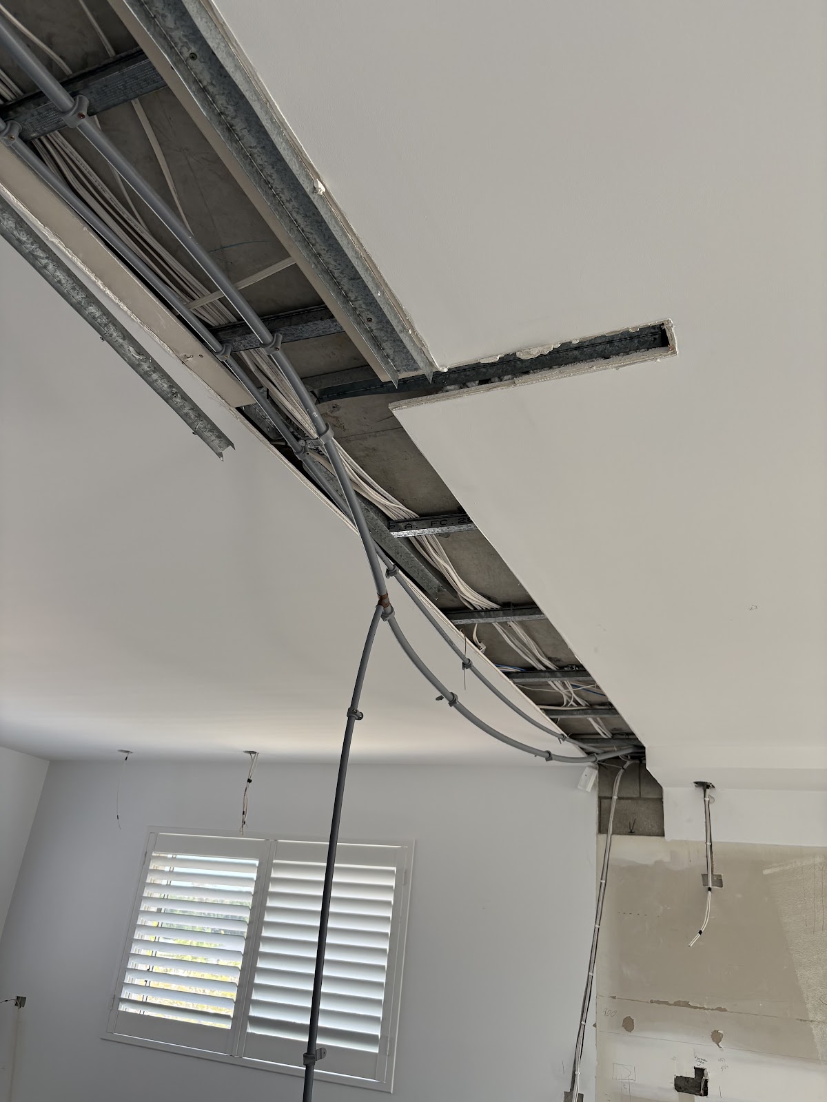Pipe and conduit runs through an open ceiling during a renovation